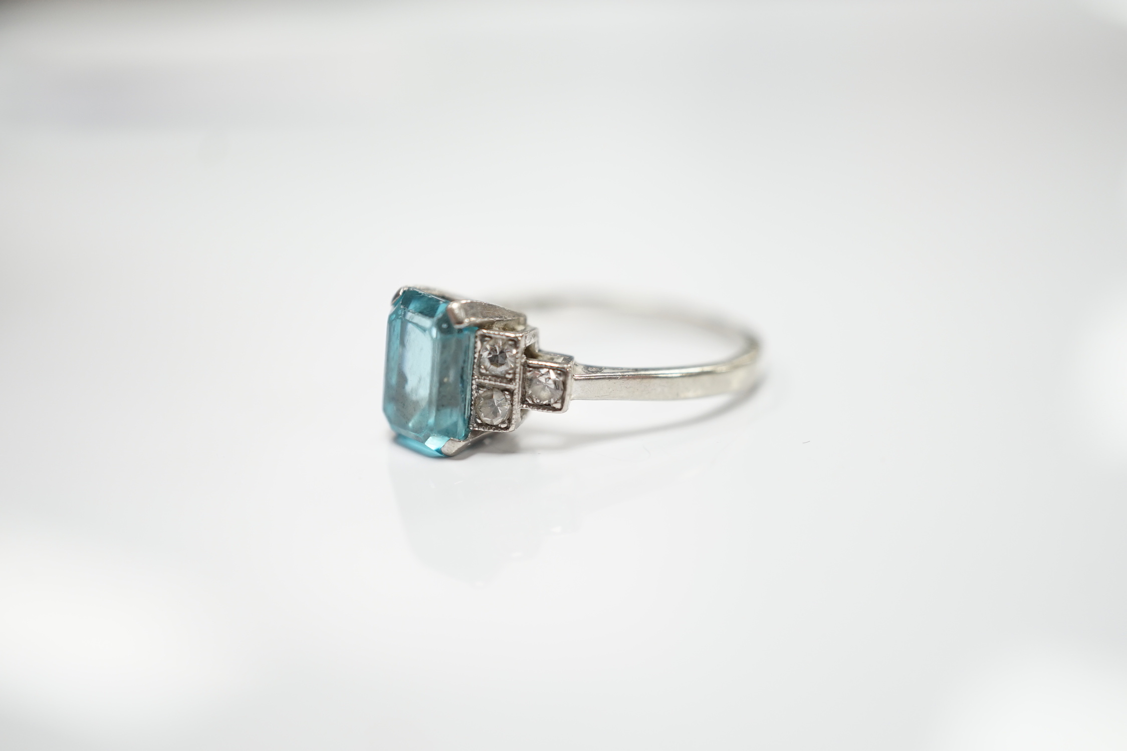 An 18ct, plat and single stone emerald cut blue zircon set ring, with six stone diamond set shoulders, size L, gross weight 2.9 grams.